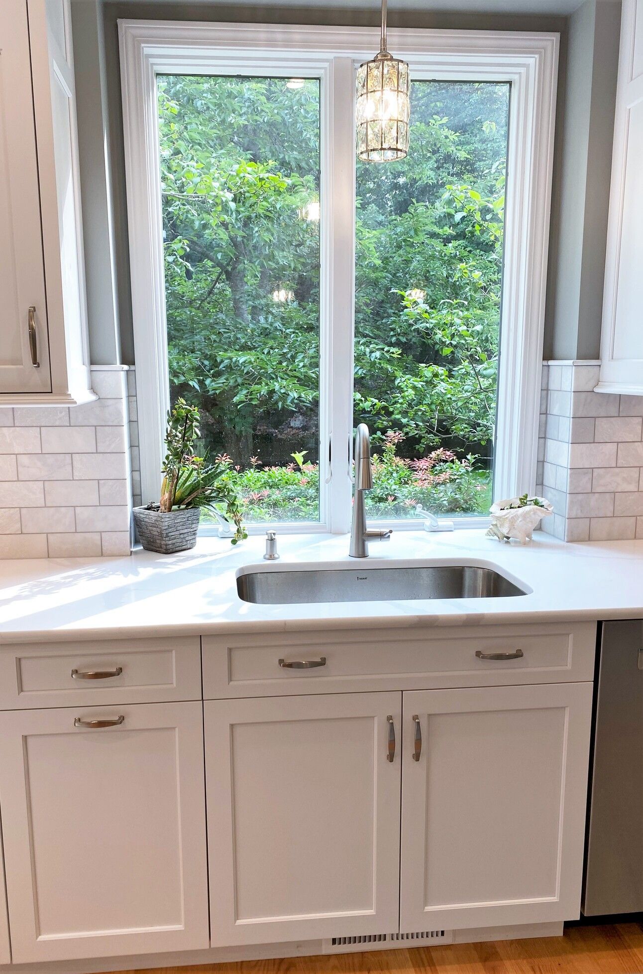 a kitchen with white cabinets, a sink, and a window