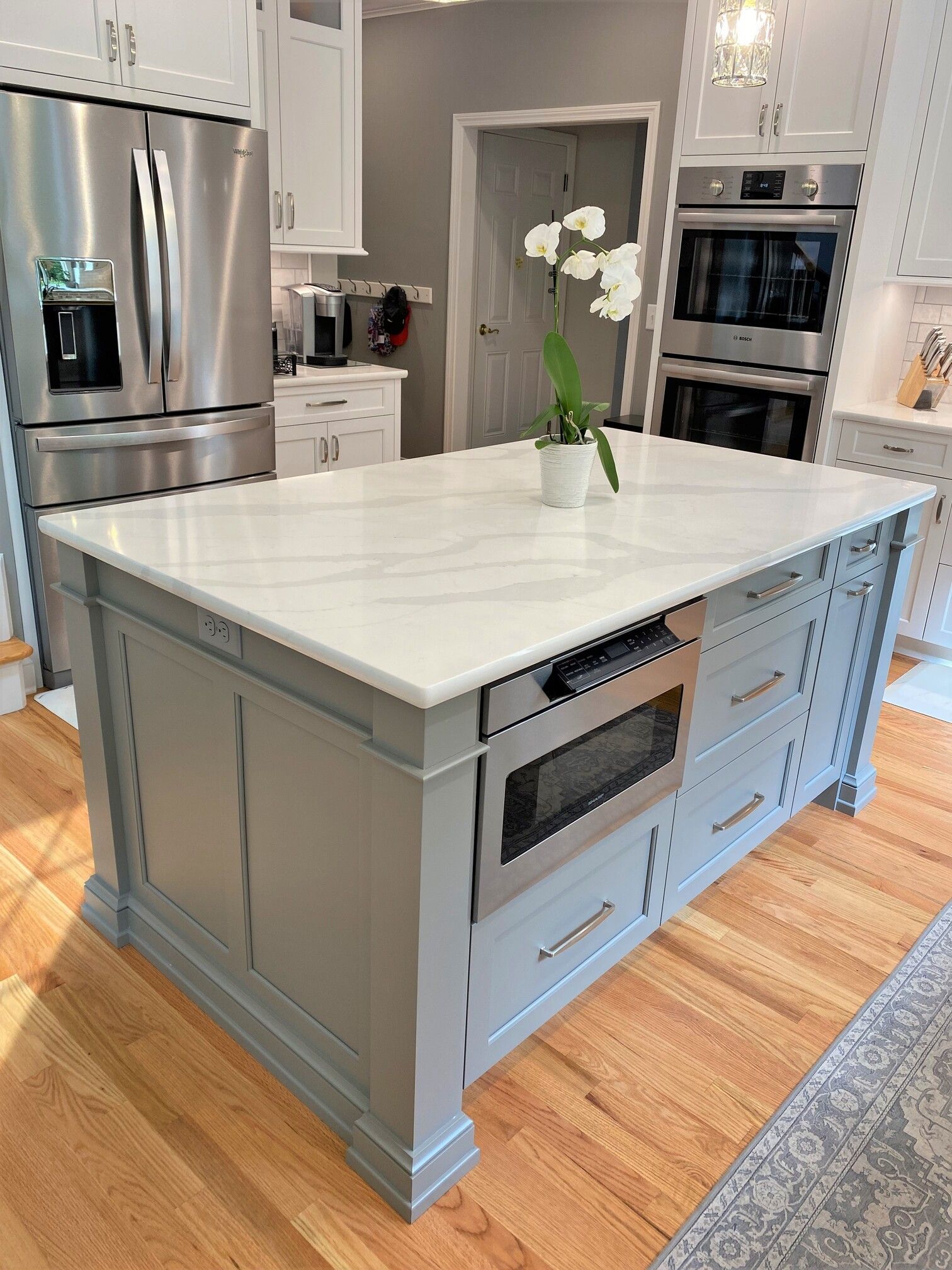 a kitchen with a large island, stainless steel appliances, and white cabinets