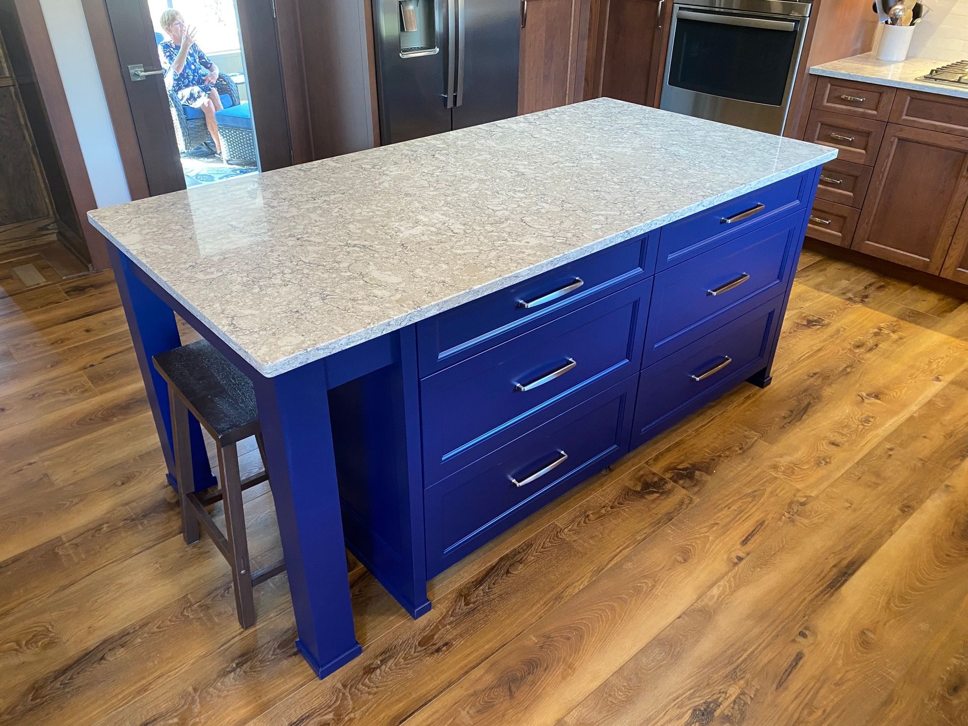 a kitchen with a blue island with drawers and a granite counter top
