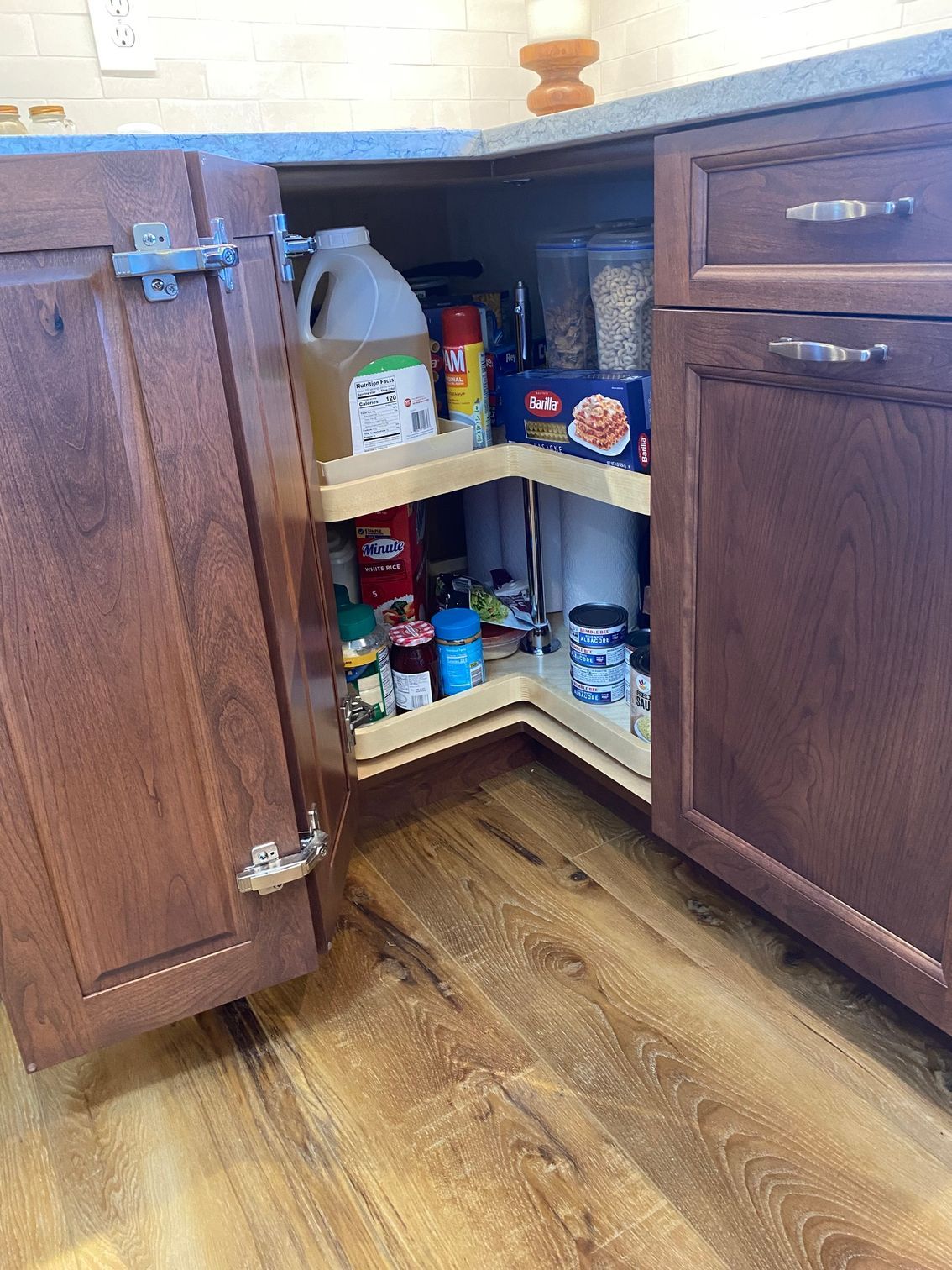 a kitchen cabinet with a corner shelf filled with food