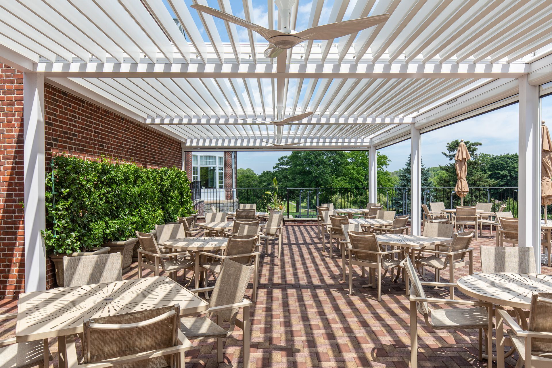 Outdoor patio with white pergola, wicker tables and chairs, and sunlit striped shadows on the floor