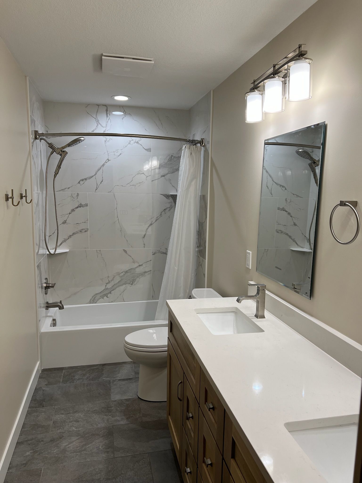 Modern bathroom with double vanity, large mirror, glass shower, and toilet.