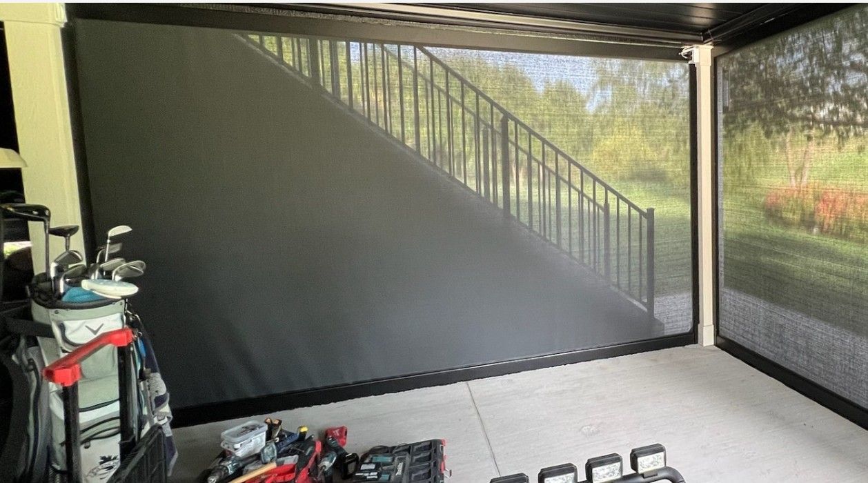 A black retractable shade covers a stairwell and golf bag in an outdoor structure.