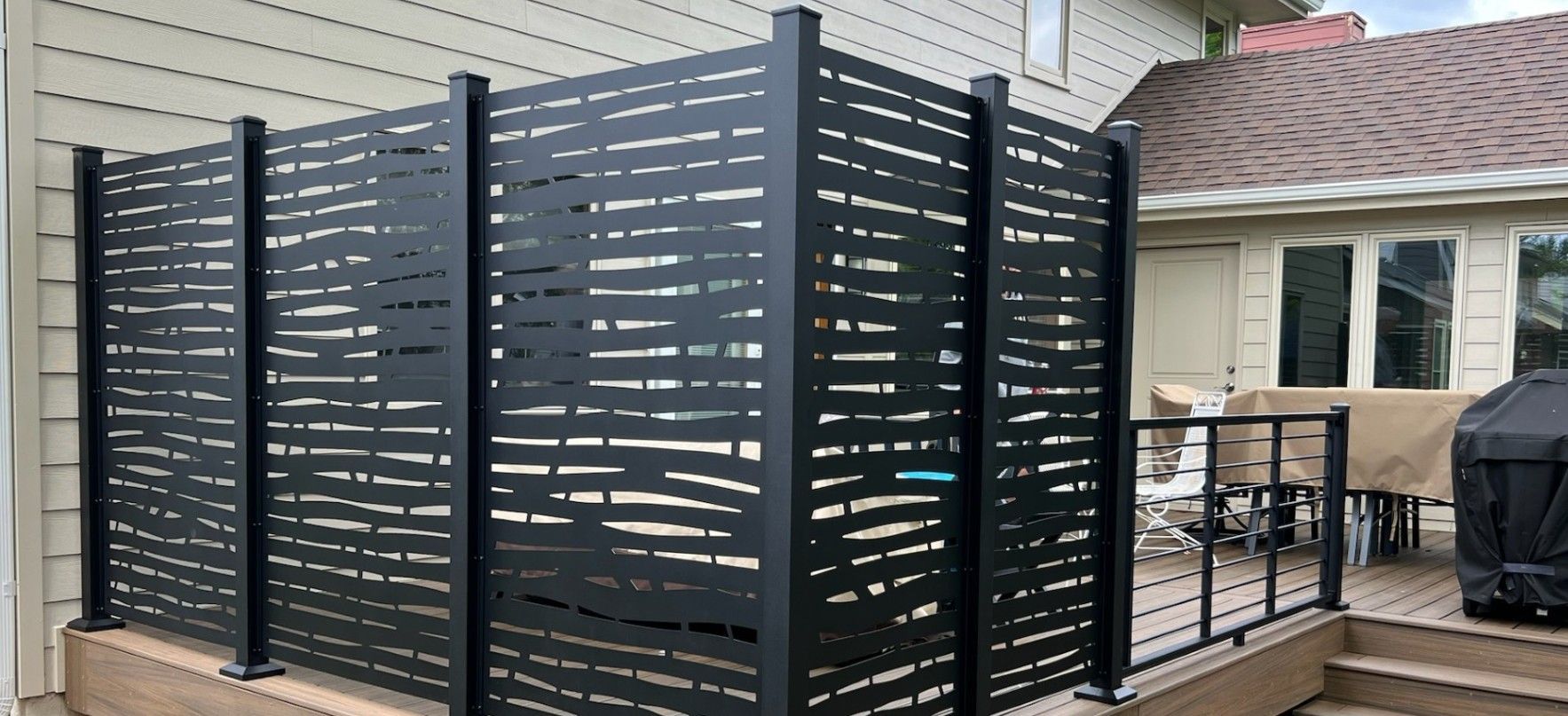 Black privacy fence on a deck, protecting the backyard of a house.