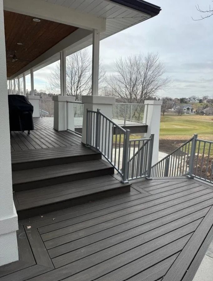Deck with stairs and metal railings overlooking a golf course on a cloudy day.