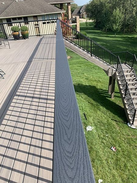 Deck with a dark gray railing and steps leading down to a green lawn.