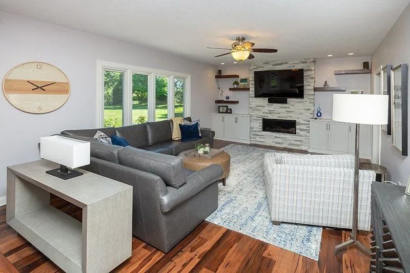 Living room with gray sectional, fireplace, TV, and wooden floor.