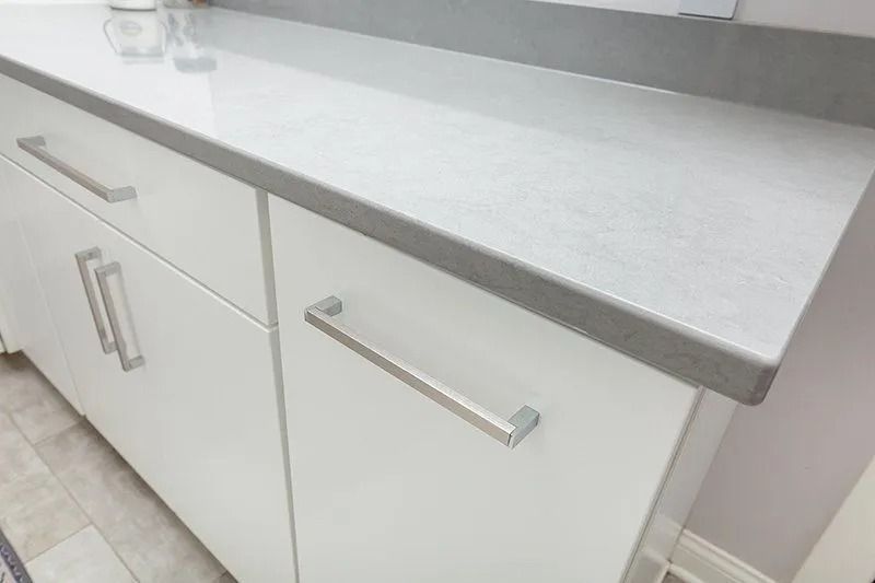 White cabinets with silver handles and a light gray countertop.
