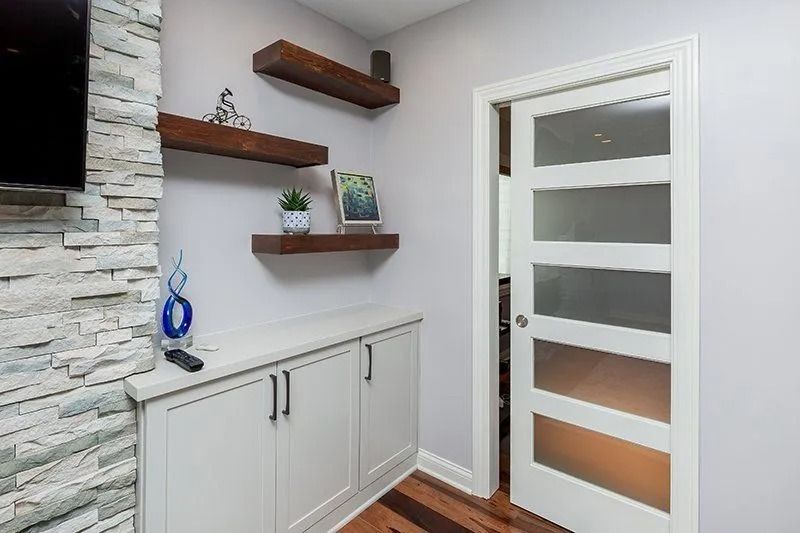 Built-in cabinets and floating shelves on a wall, next to a door with frosted glass panes.