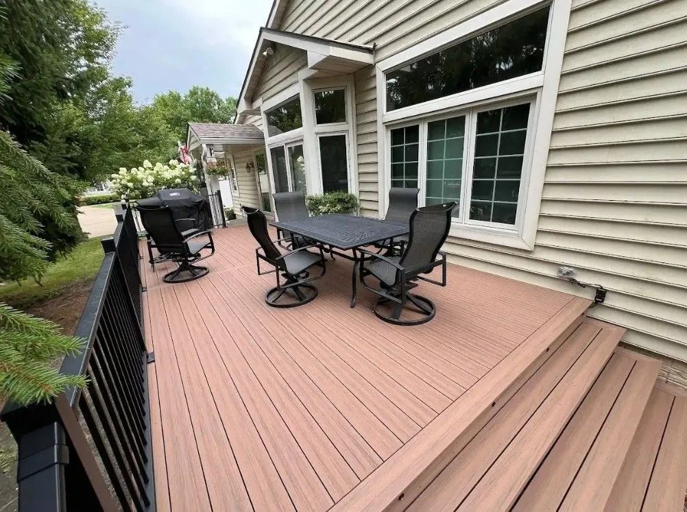 Wooden deck with outdoor furniture next to a house with large windows.