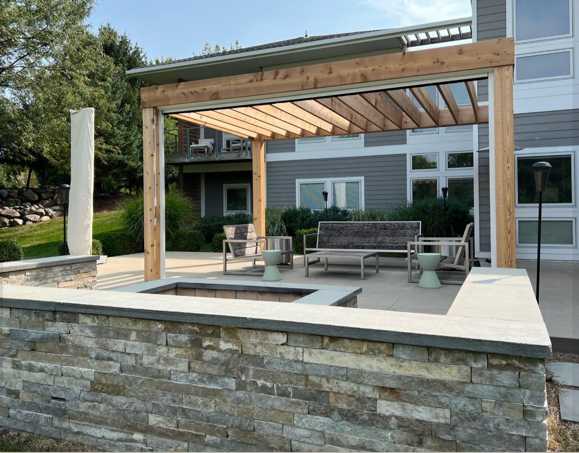 Outdoor patio with wooden pergola, stone wall, and seating.
