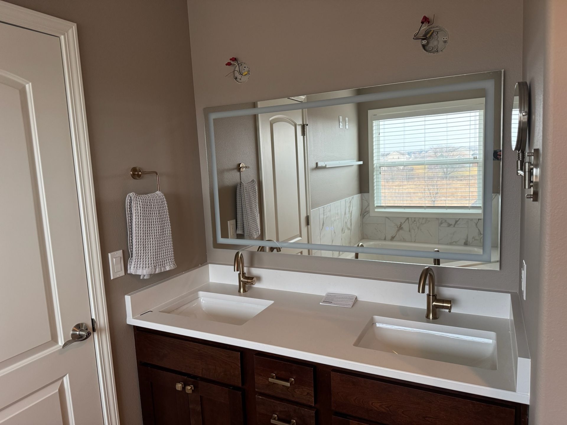 Bathroom vanity with double sinks, large mirror, and dark wood cabinets beneath.