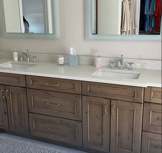 Double vanity bathroom with dark wood cabinets, white countertop, twin sinks, and wall mirrors