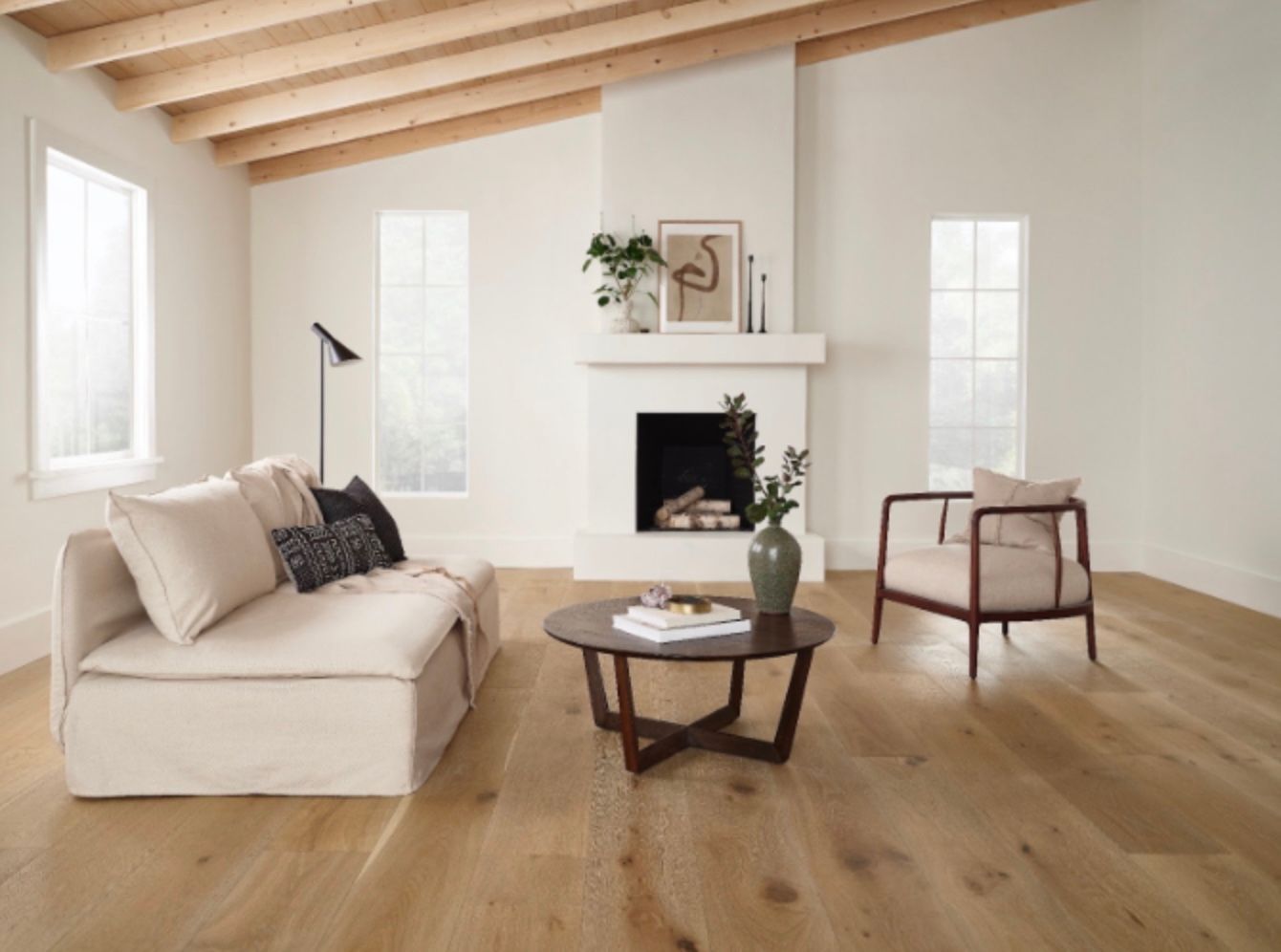 Living room with light wood floor, white walls, couch, armchair, coffee table, and fireplace.