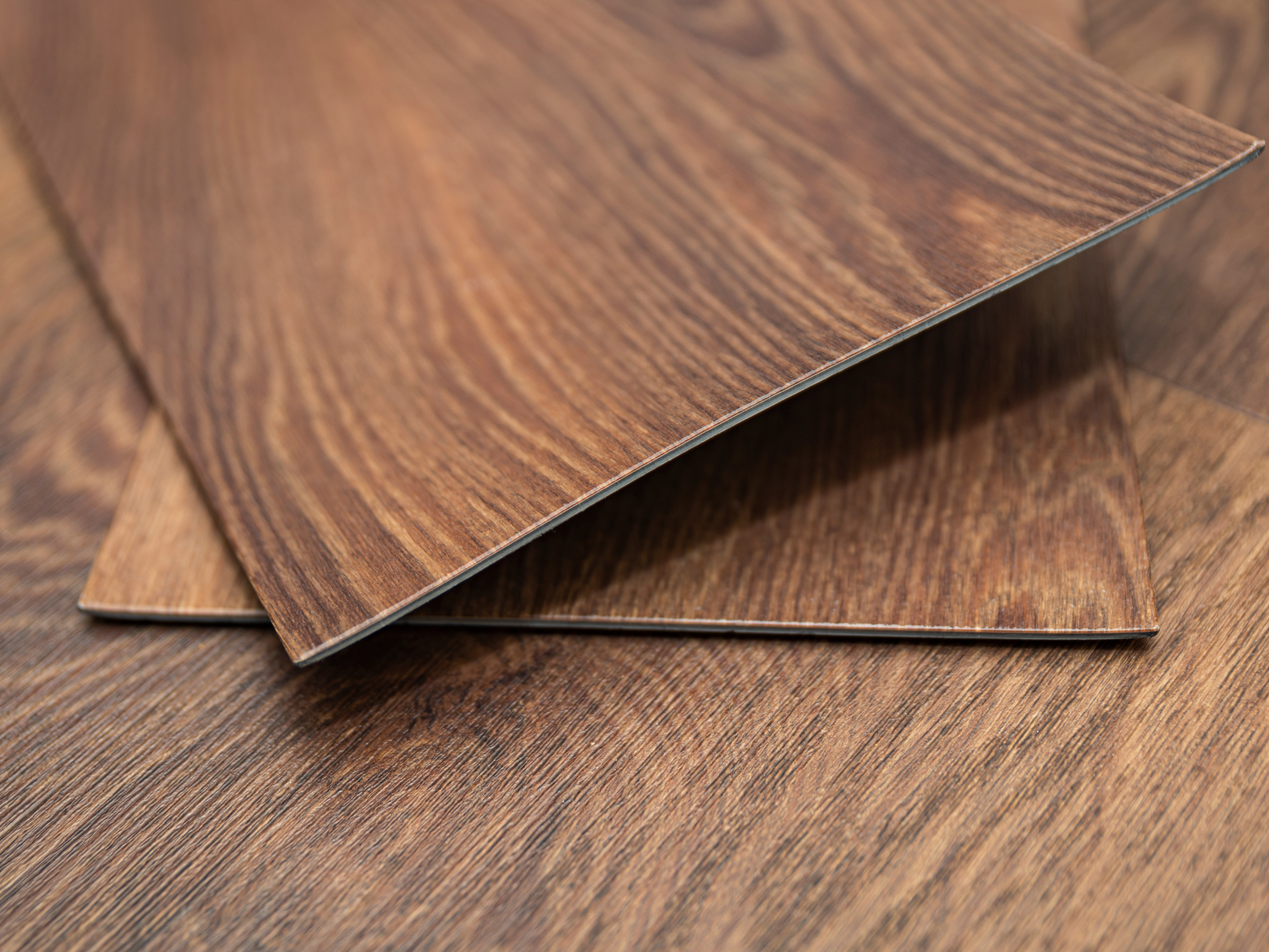 Close-up of wood-grain flooring planks in shades of brown, overlapping.