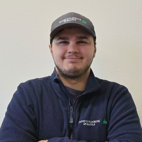 Man in gray hat and blue jacket, smiling at the camera.