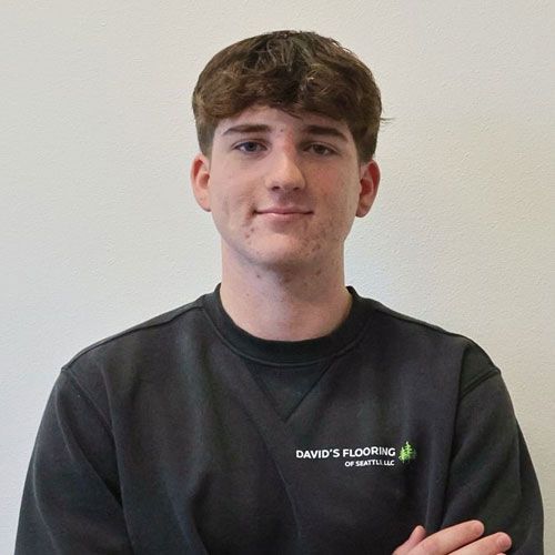 Young man with brown hair, arms crossed, wearing a black sweatshirt with 
