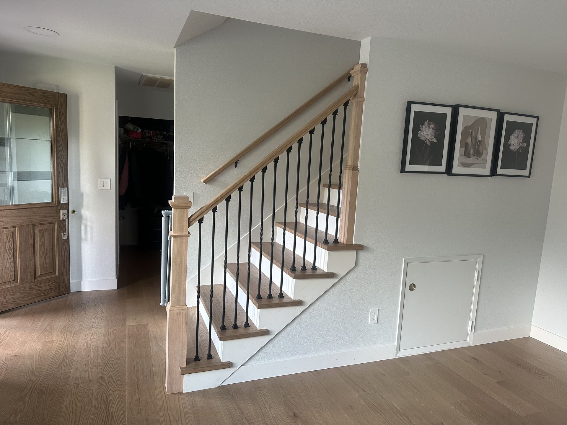 Wooden staircase with black iron spindles, white steps, and light gray walls.