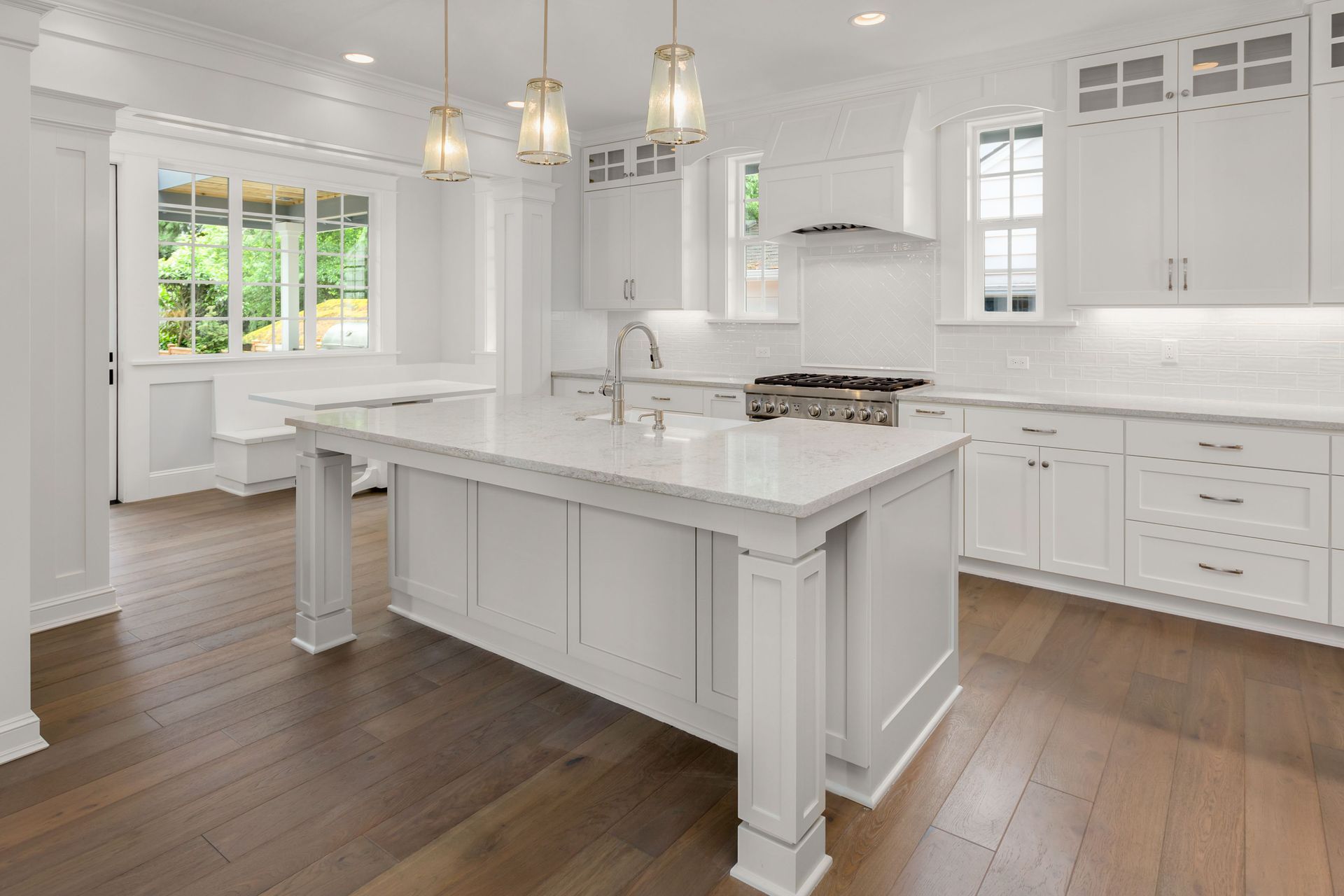 Modern kitchen with island, wood cabinets, white countertops, and pendant lights.