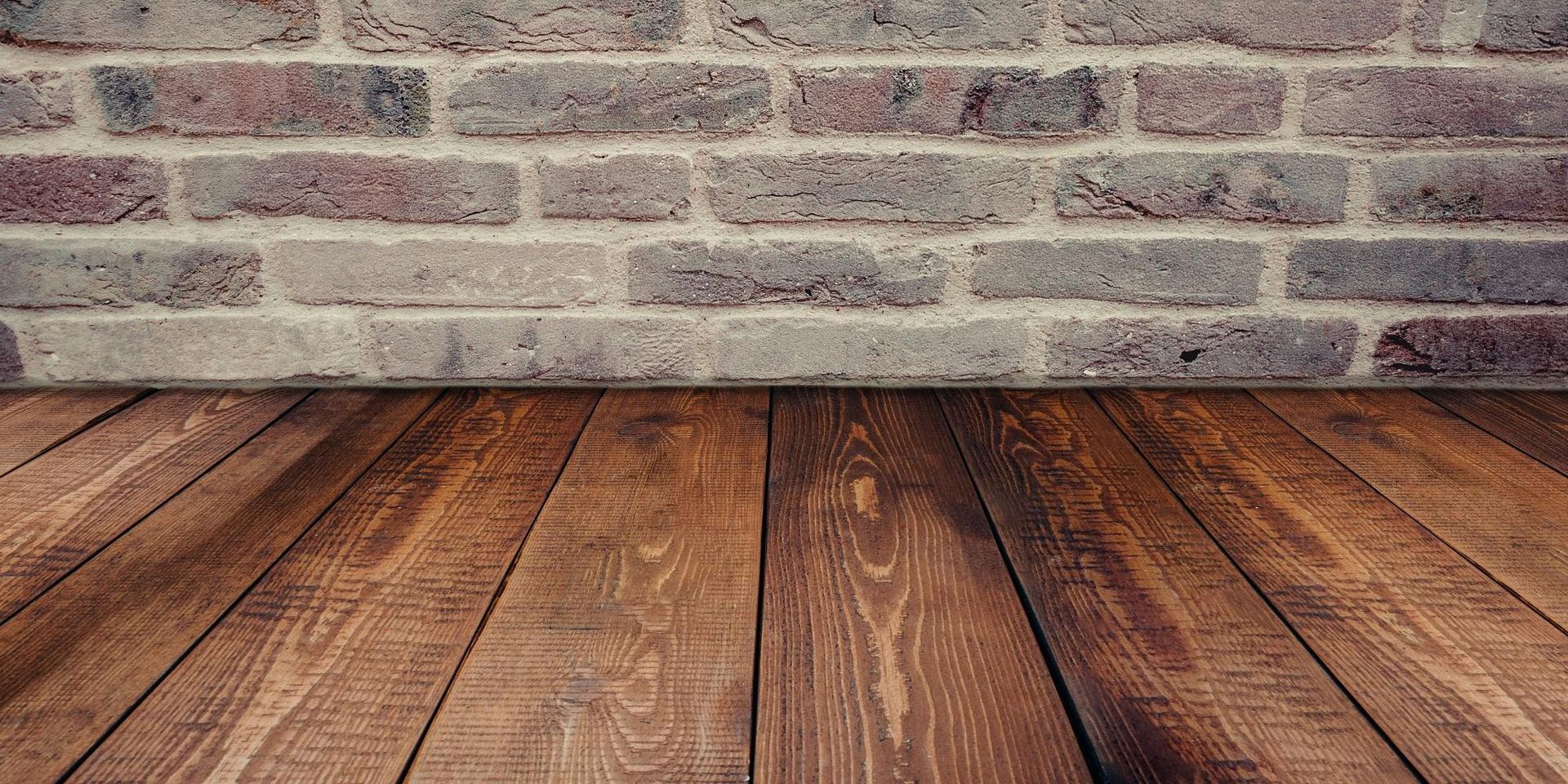 Wooden floor with a brick wall in the background.