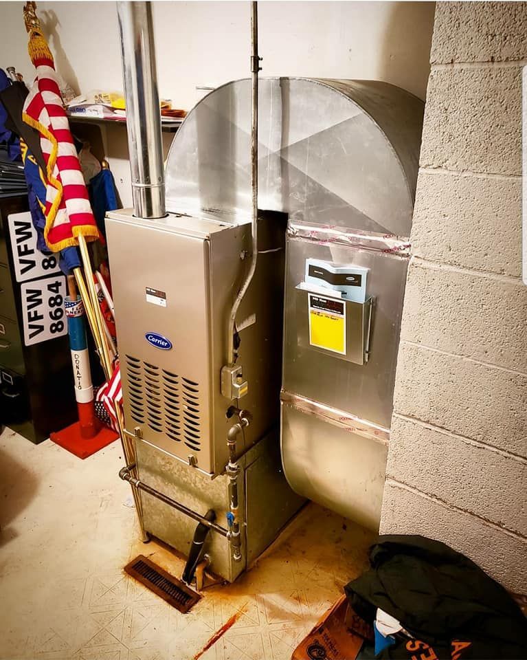 A silver heater is sitting in a room next to a brick wall.
