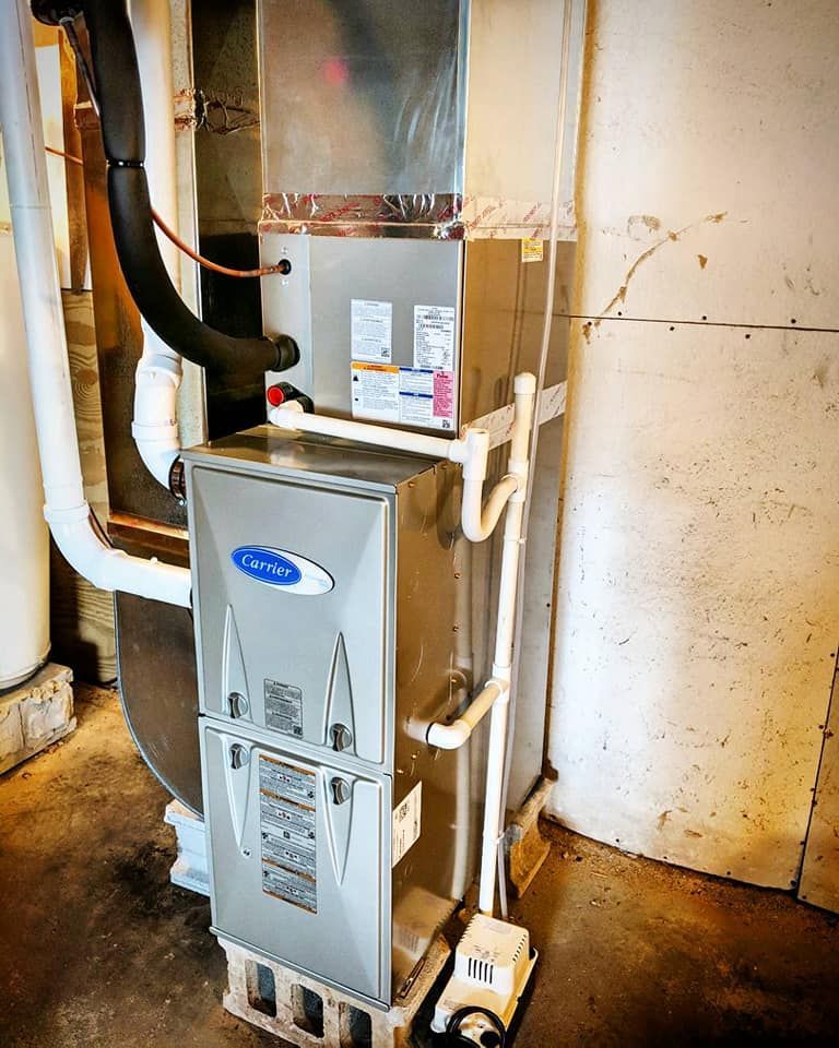 A carrier air conditioner is sitting in a basement next to a wall.