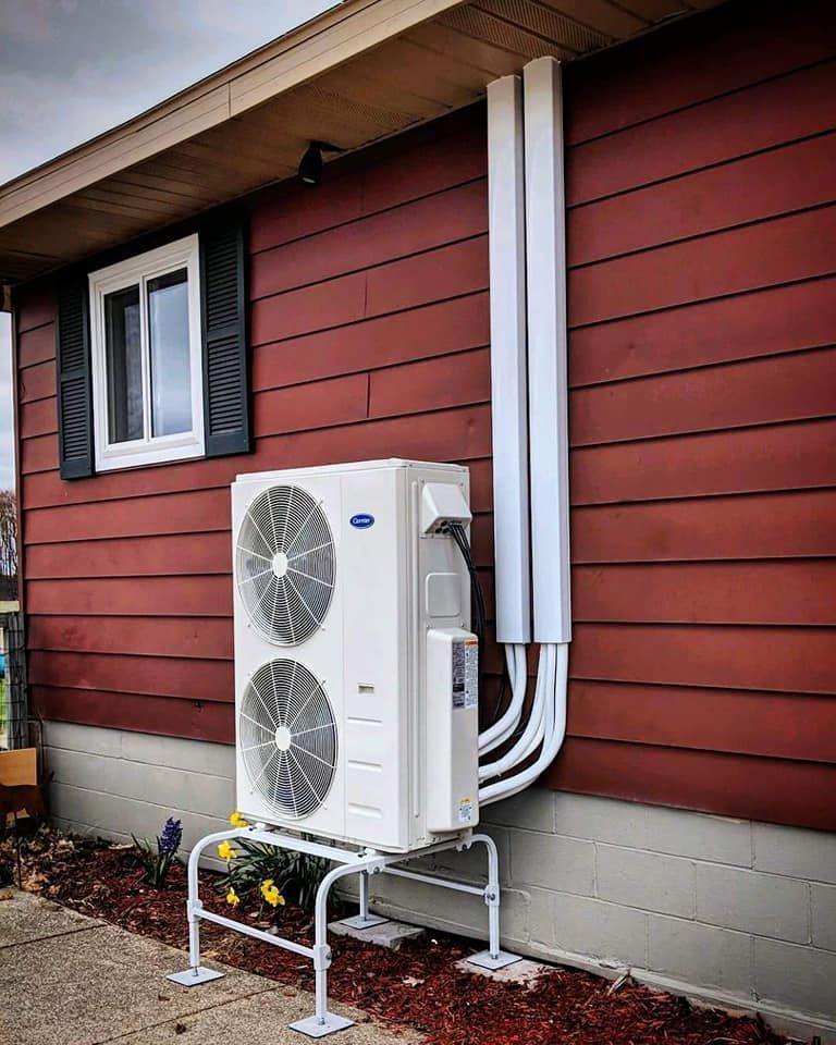 A red house with a white air conditioner on the side of it.