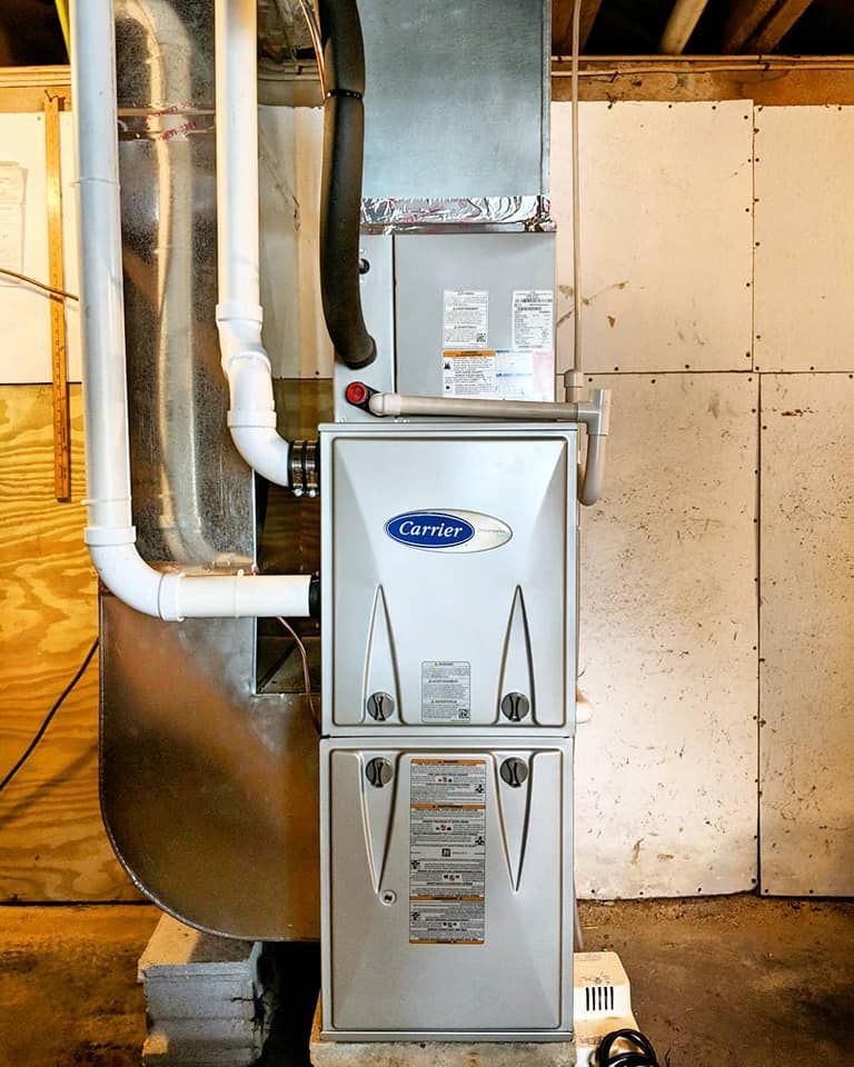 A carrier air conditioner is sitting in a basement next to a wall.