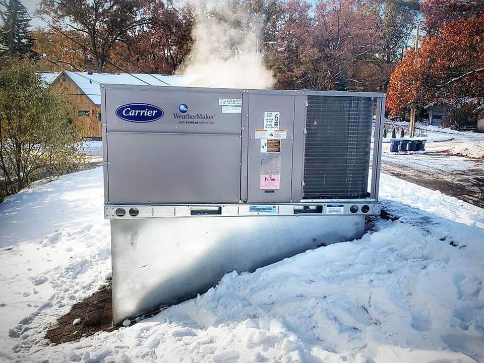 A carrier air conditioner is sitting in the snow