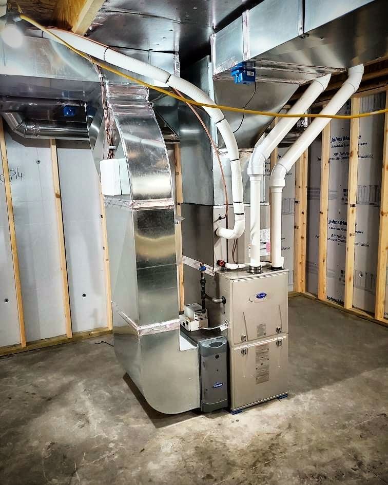 A stainless steel air conditioner is sitting in a basement.