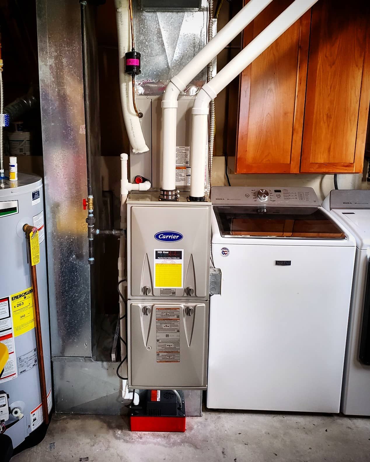 A washer and dryer are sitting next to a furnace in a basement.