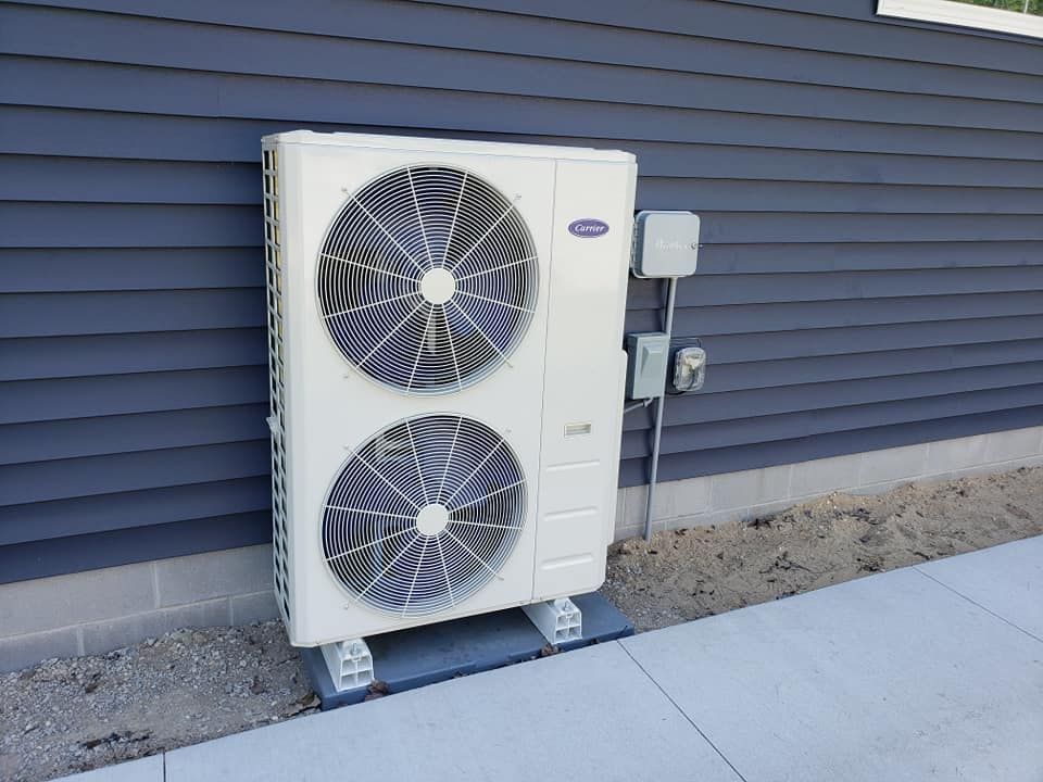 A large white air conditioner is sitting on the side of a building.