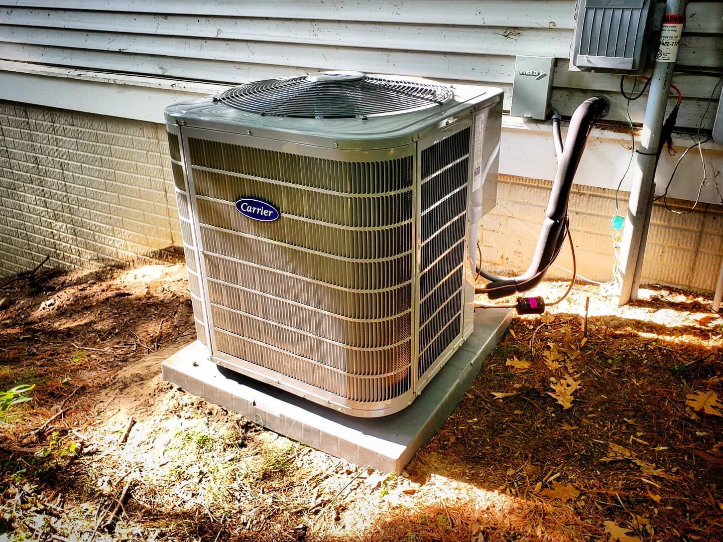 A carrier air conditioner is sitting outside of a house.