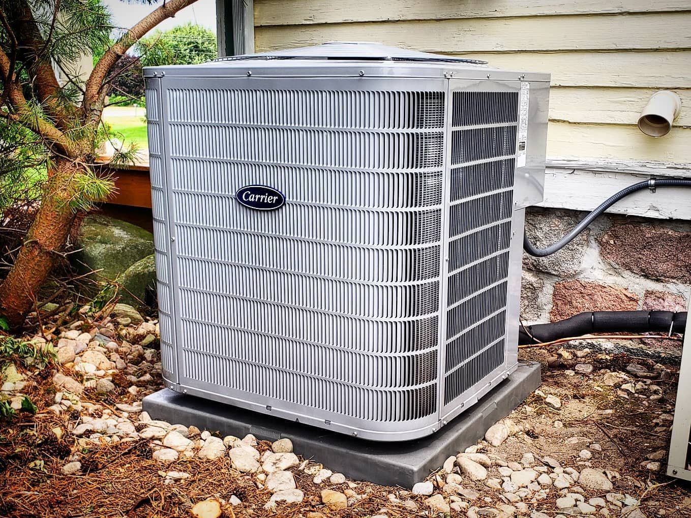 A large air conditioner is sitting outside of a house.