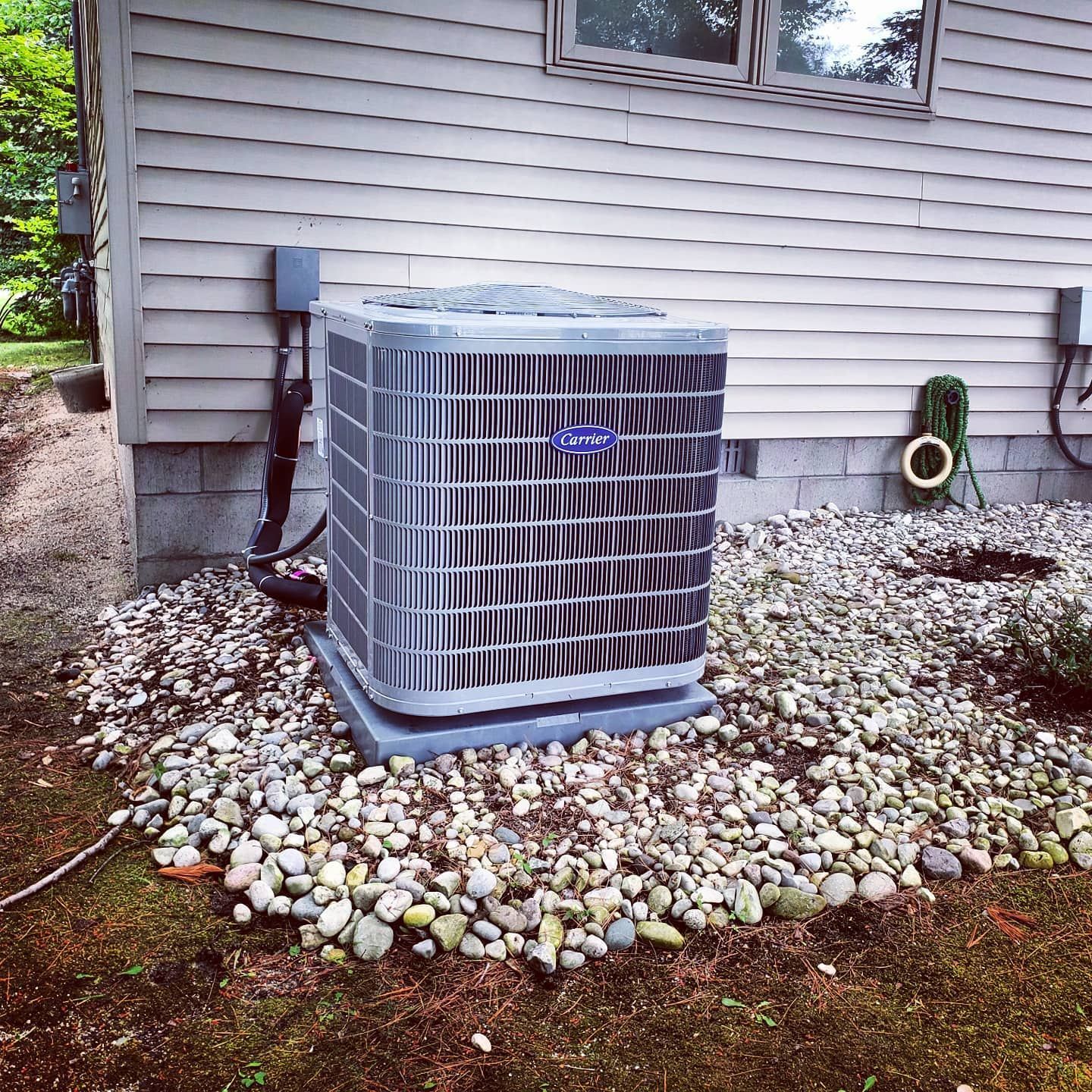A carrier air conditioner is sitting outside of a house