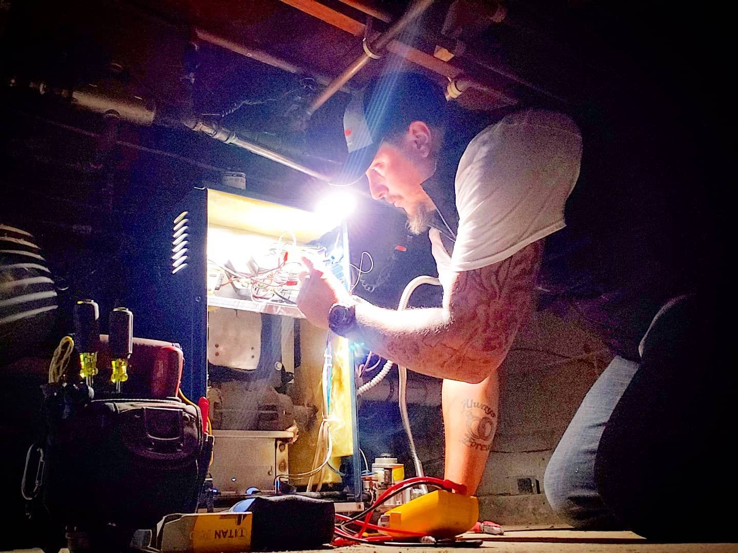 A man is working under a ceiling with a flashlight