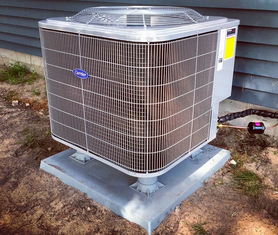 A carrier air conditioner is sitting on top of a concrete base.