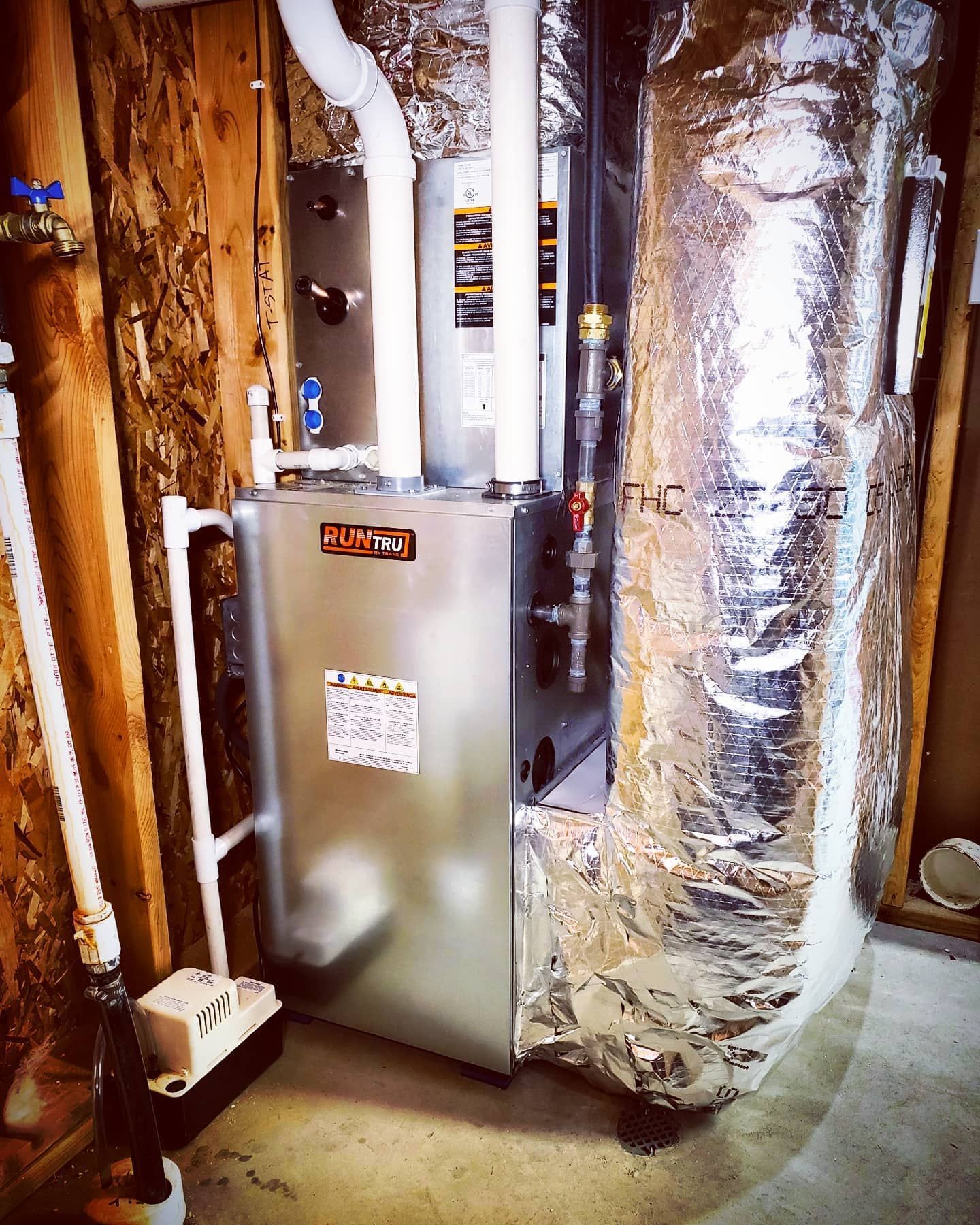 A stainless steel furnace is sitting in a basement.