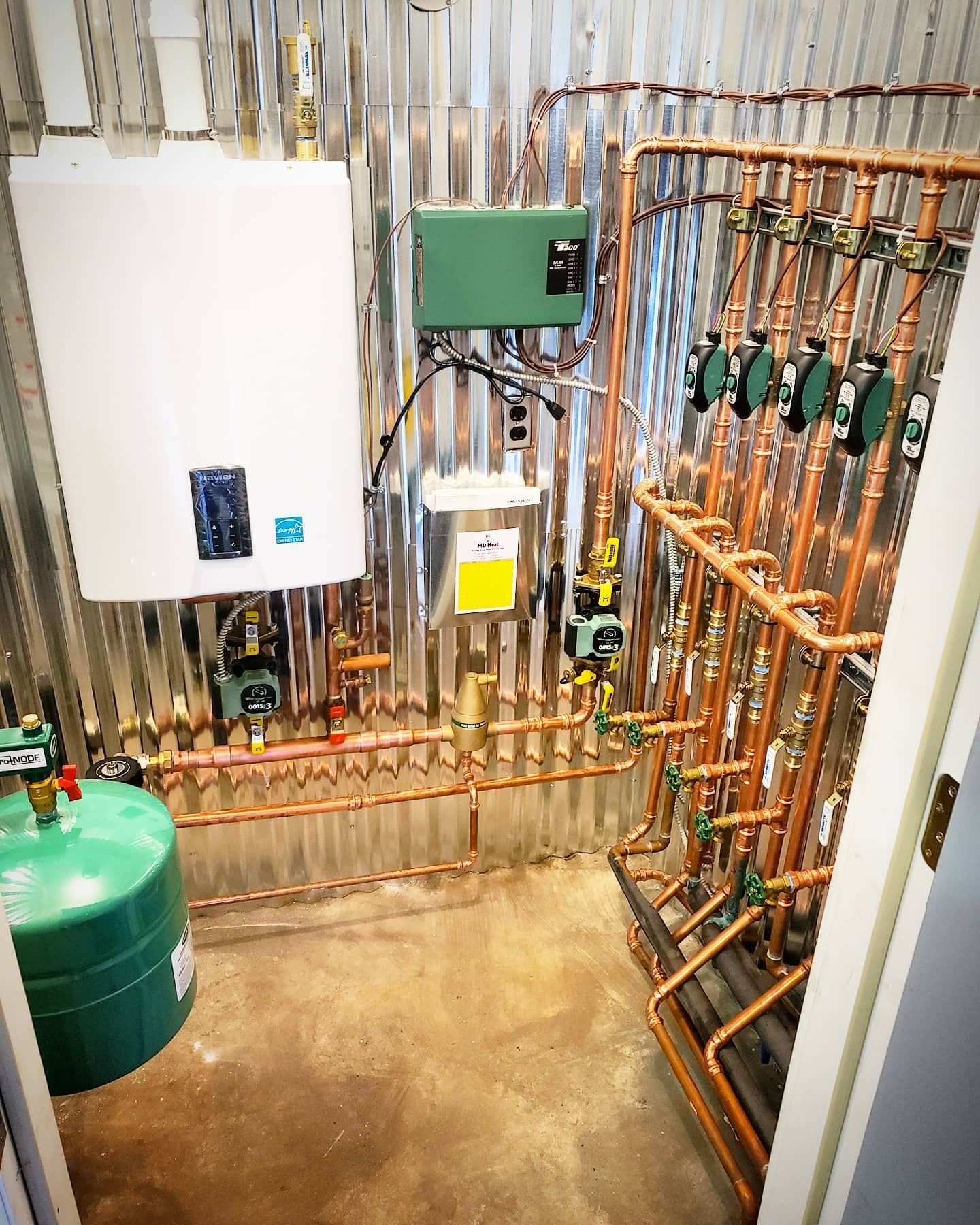 A room with a lot of pipes and a green tank.