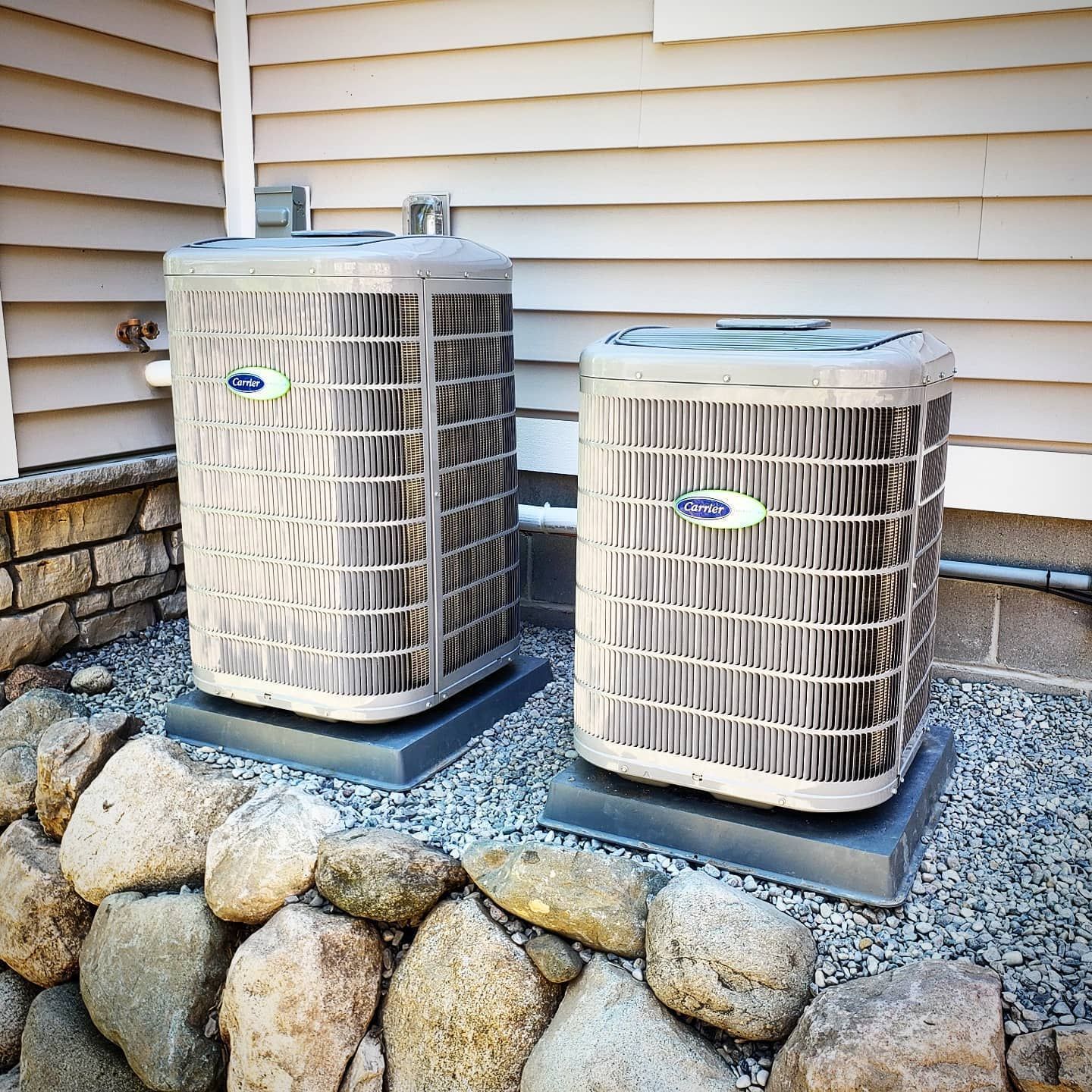 Two carrier air conditioners are sitting outside of a house