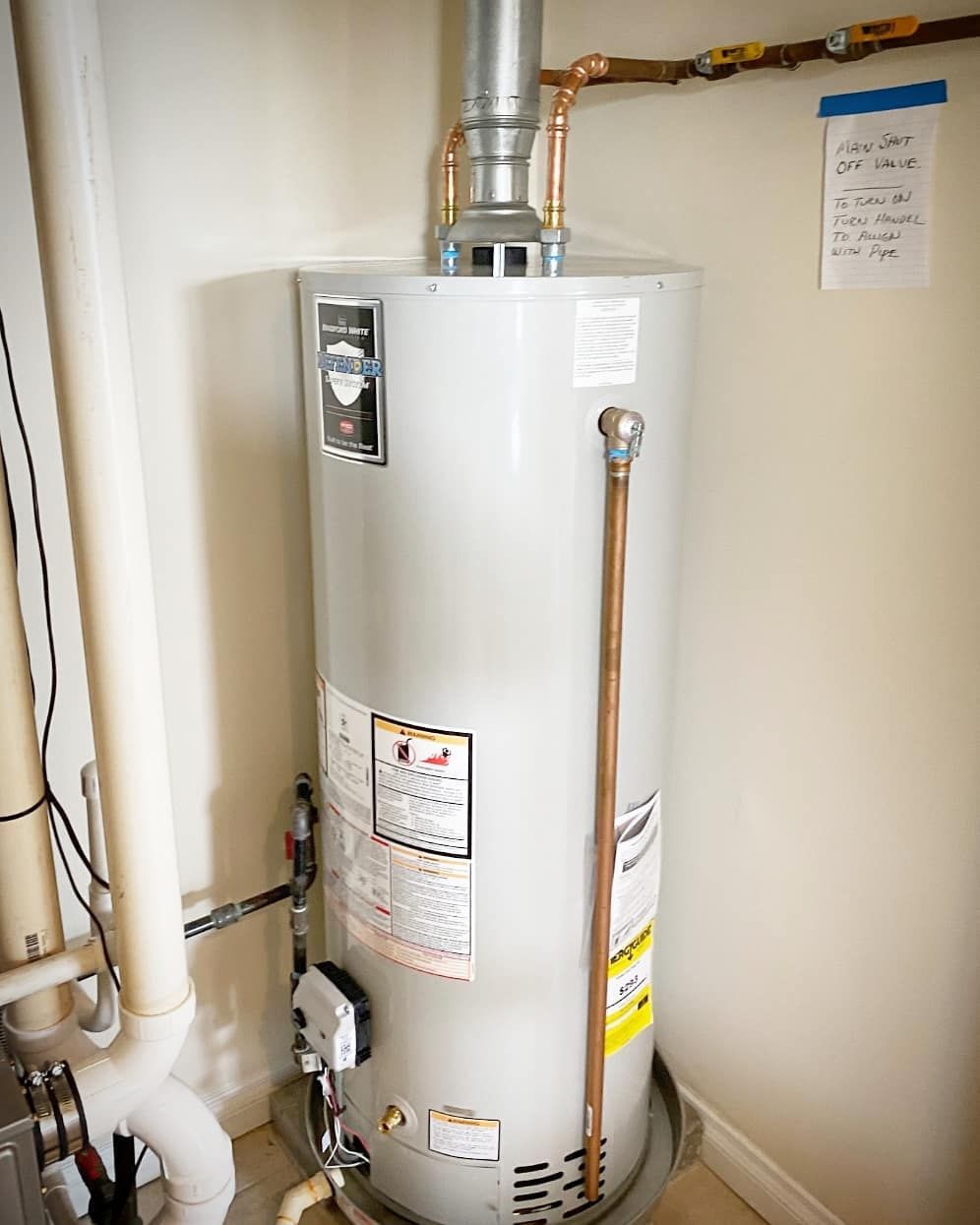 A water heater is sitting in a room next to a pipe.