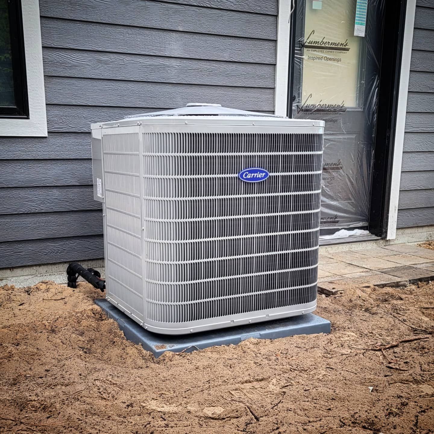 A carrier air conditioner is sitting outside of a house