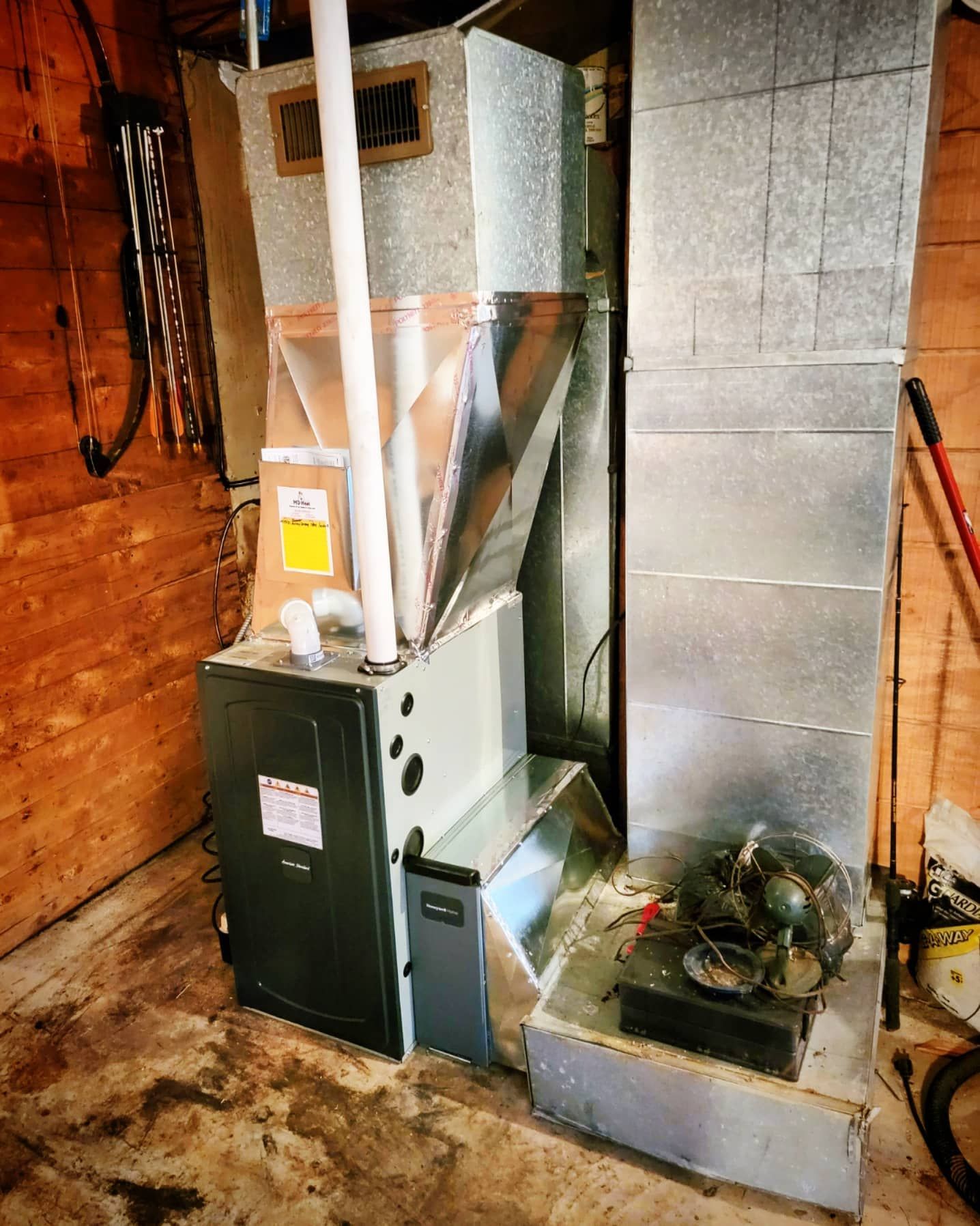 An air conditioner is sitting in a room next to a fan.