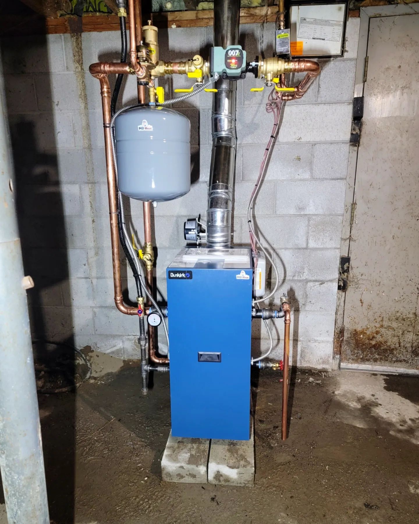 A blue boiler in a basement with copper pipes