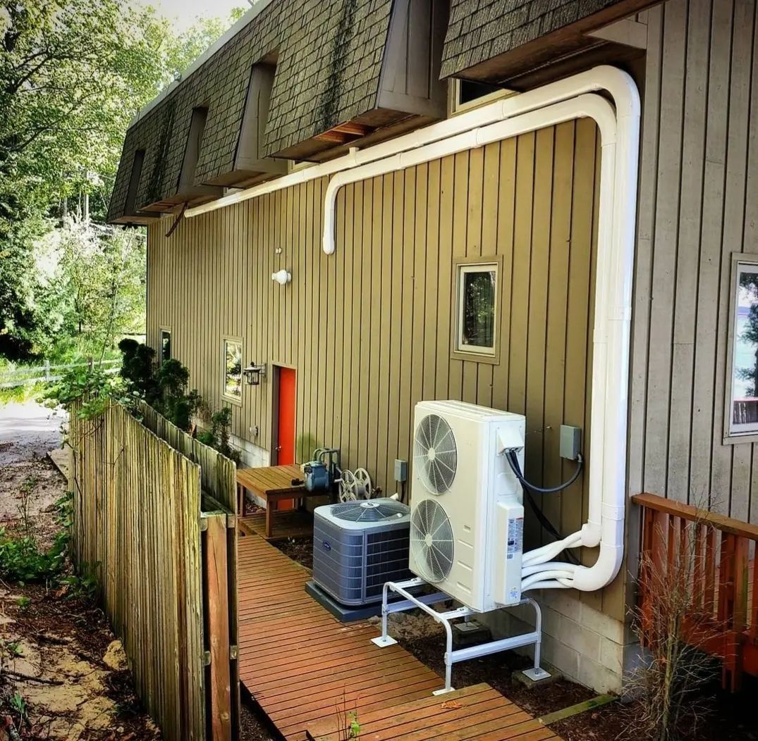A large air conditioner is attached to the side of a house