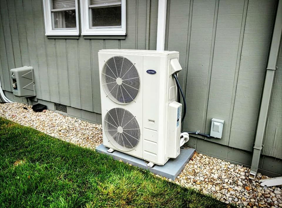 A white air conditioner is sitting on the side of a house.