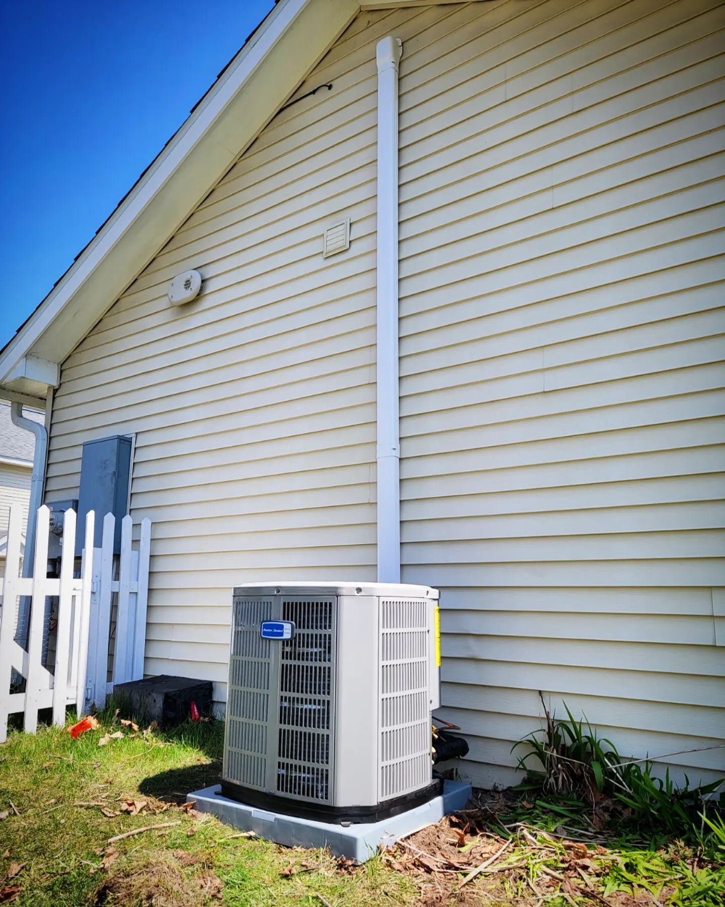 An air conditioner is sitting on the side of a house.