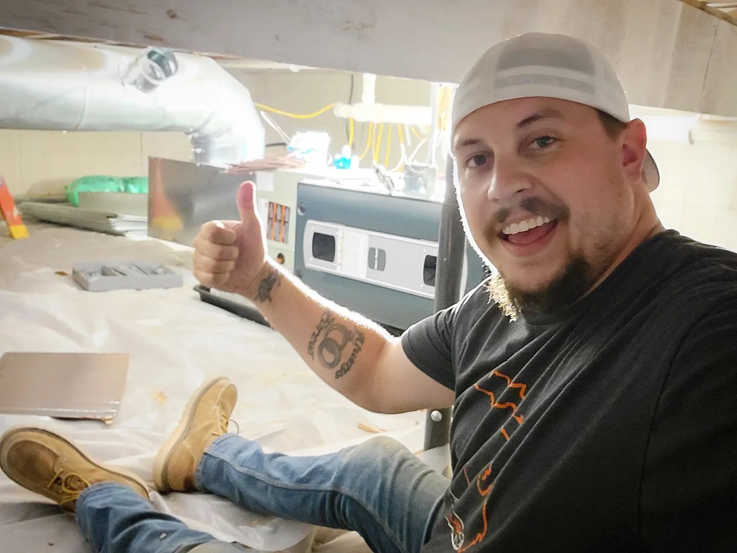 A man is giving a thumbs up while sitting on the floor.