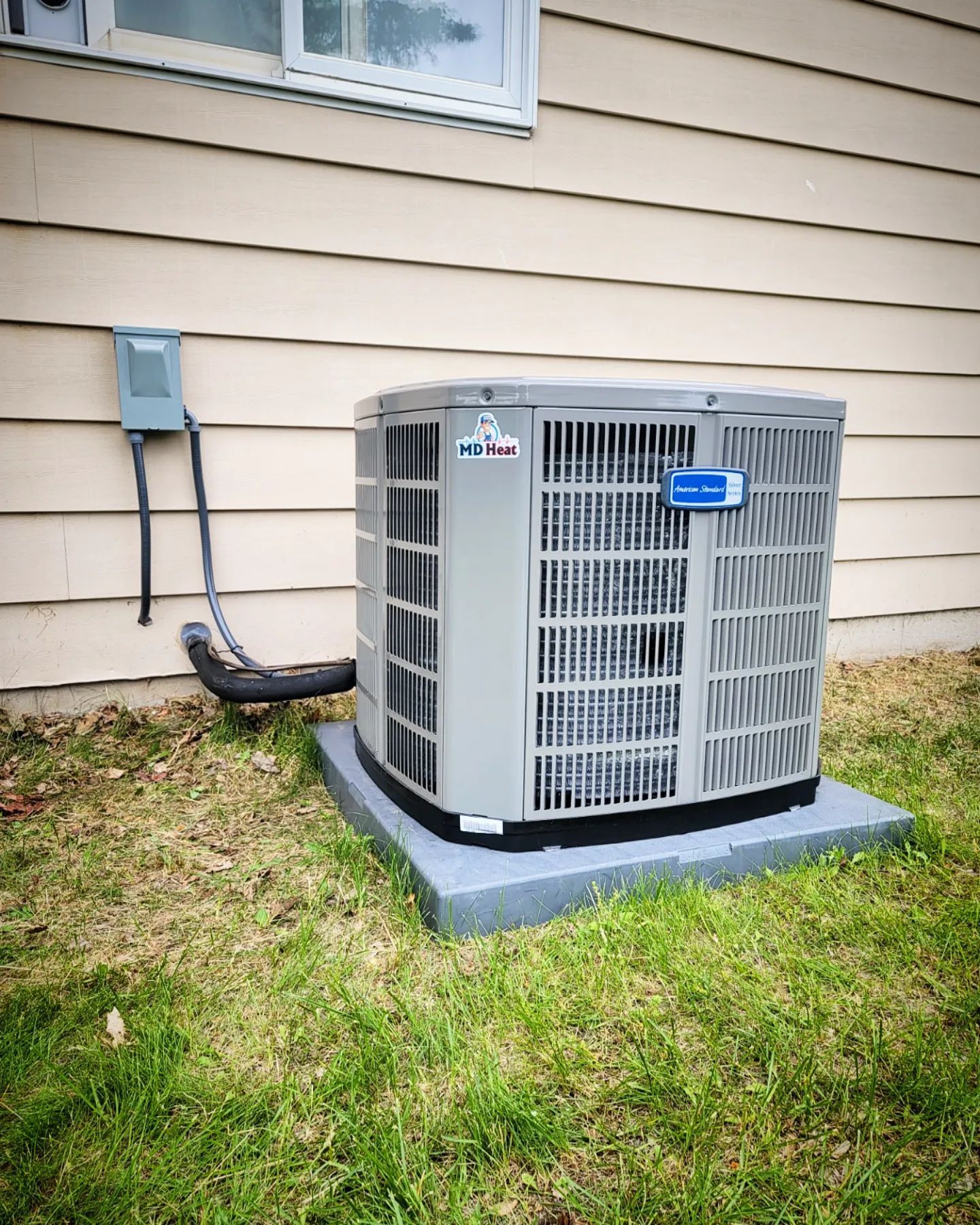 An air conditioner is sitting on the side of a house.