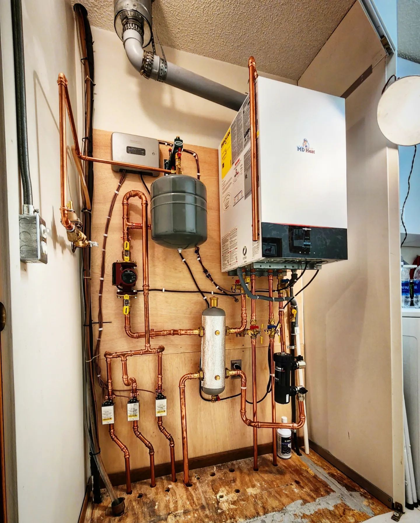 A room with copper pipes and a boiler on the wall
